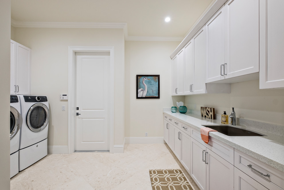 Inspiration for a large traditional galley dedicated laundry room in Miami with an undermount sink, recessed-panel cabinets, white cabinets, quartz benchtops, beige walls and a side-by-side washer and dryer.