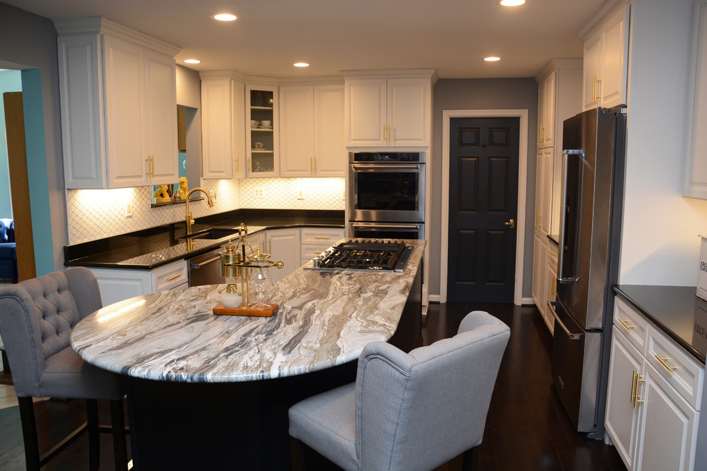 Photo of a large traditional u-shaped kitchen pantry in Baltimore with a single-bowl sink, raised-panel cabinets, white cabinets, granite benchtops, white splashback, ceramic splashback, stainless steel appliances, dark hardwood floors, with island and brown floor.