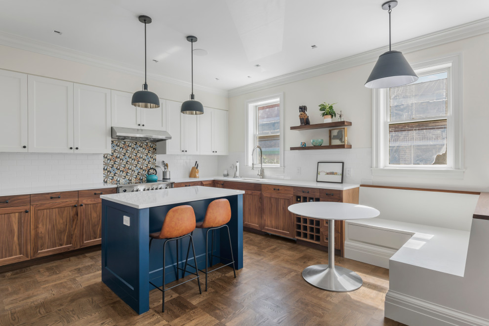 Photo of a large transitional l-shaped eat-in kitchen in New York with a drop-in sink, shaker cabinets, dark wood cabinets, quartz benchtops, multi-coloured splashback, ceramic splashback, stainless steel appliances, dark hardwood floors, with island, brown floor and white benchtop.