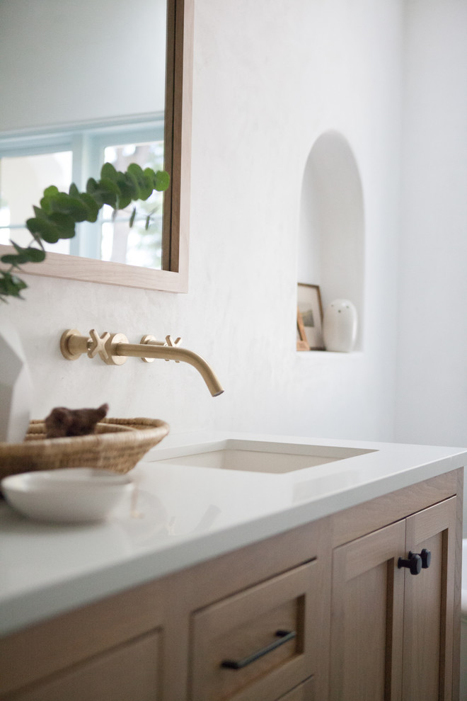 This is an example of a mid-sized mediterranean master bathroom in Los Angeles with recessed-panel cabinets, medium wood cabinets, a freestanding tub, white walls, ceramic floors, an undermount sink, engineered quartz benchtops, green floor and white benchtops.
