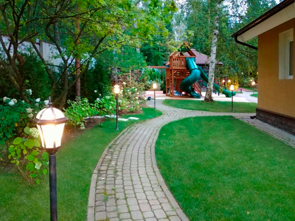 Großer, Schattiger Landhausstil Garten im Sommer, neben dem Haus mit Auffahrt, Spielgerät, Betonboden und Metallzaun in Moskau