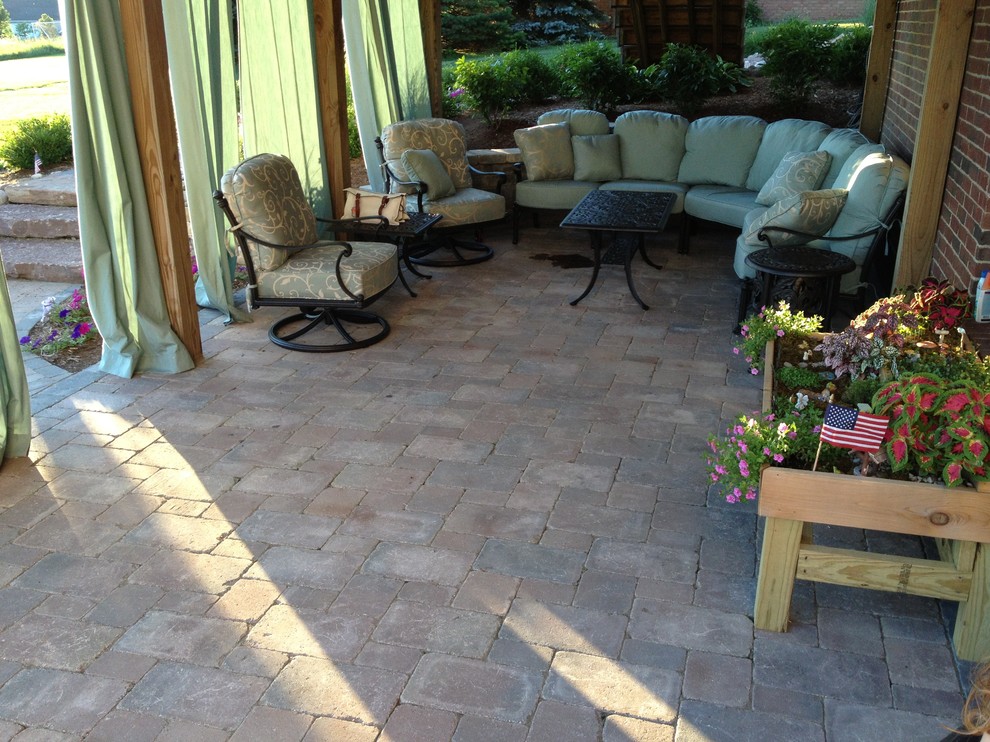 Design ideas for a mid-sized country backyard patio in Detroit with a fire feature, brick pavers and no cover.