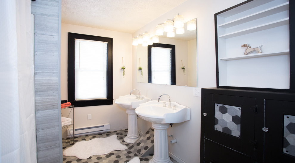 Example of a small transitional gray tile vinyl floor alcove bathtub design with furniture-like cabinets, black cabinets, a two-piece toilet, white walls and a pedestal sink