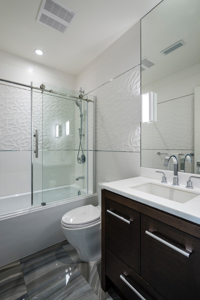 Mid-sized contemporary bathroom in Vancouver with flat-panel cabinets, black cabinets, a corner tub, a one-piece toilet, white tile, porcelain tile, grey walls, marble floors, an undermount sink, quartzite benchtops and grey floor.