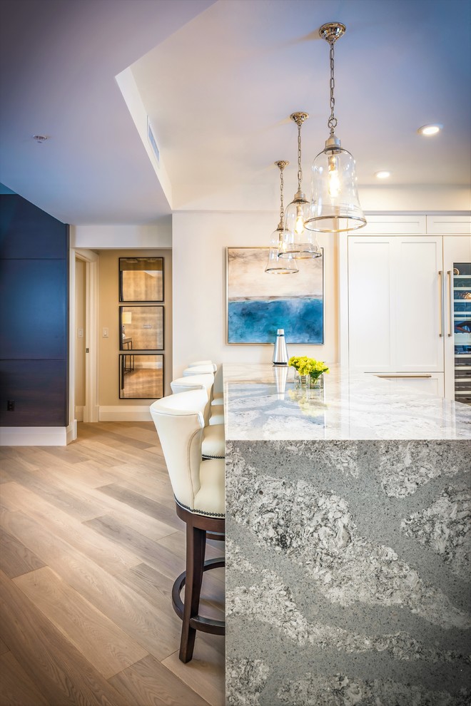 This is an example of an expansive transitional u-shaped eat-in kitchen in Miami with a drop-in sink, shaker cabinets, white cabinets, granite benchtops, blue splashback, subway tile splashback, panelled appliances, light hardwood floors and multiple islands.