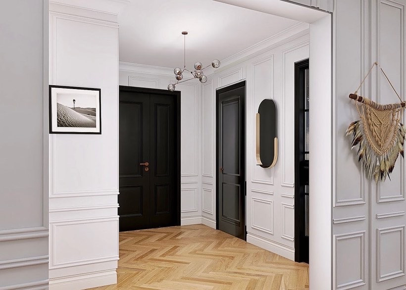 Modern inredning av en mellanstor foajé, med vita väggar, ljust trägolv, en dubbeldörr, en svart dörr och beiget golv