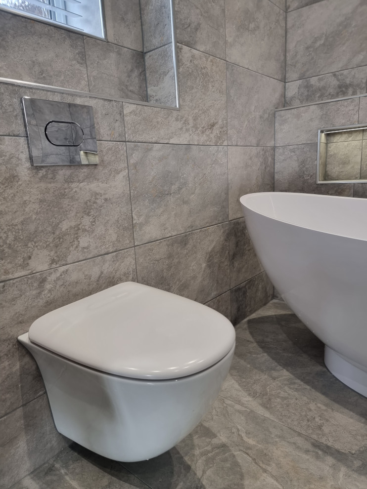 Bathroom - large contemporary master gray tile and porcelain tile porcelain tile, gray floor and double-sink bathroom idea in West Midlands with flat-panel cabinets, gray cabinets, a wall-mount toilet, gray walls, a wall-mount sink, a hinged shower door, a niche and a floating vanity