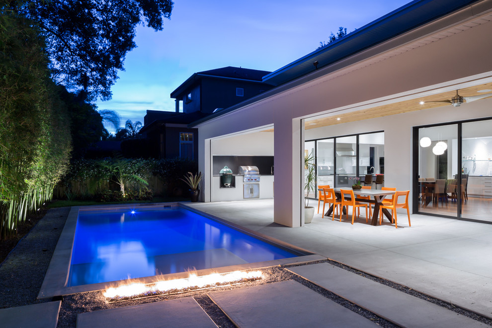 Inspiration for a large midcentury backyard patio in Orlando with a fire feature, concrete slab and a roof extension.