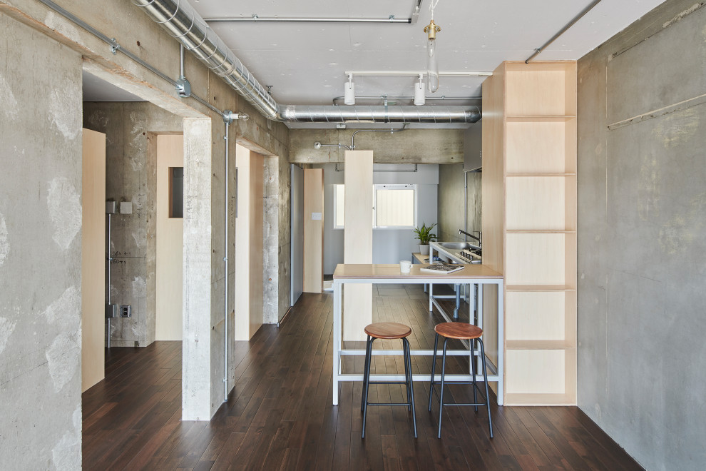 東京都下にあるお手頃価格の中くらいなインダストリアルスタイルのおしゃれなリビング (グレーの壁、濃色無垢フローリング、暖炉なし、塗装板張りの暖炉まわり、据え置き型テレビ、茶色い床、表し梁、塗装板張りの壁) の写真