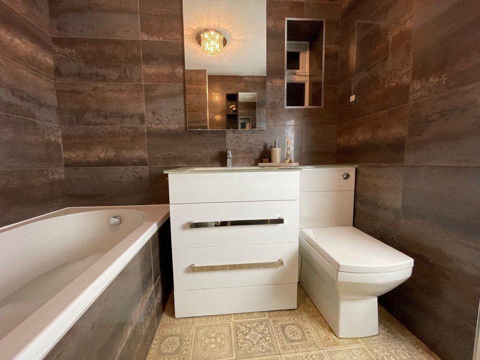 Mid-sized modern bathroom in Buckinghamshire with flat-panel cabinets, white cabinets, a drop-in tub, a wall-mount toilet, porcelain tile, porcelain floors, an integrated sink, glass benchtops, brown floor, white benchtops, a niche, a single vanity and a freestanding vanity.