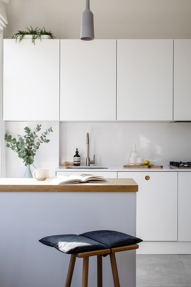 Inspiration for a small modern galley kitchen in London with an undermount sink, flat-panel cabinets, quartzite benchtops, white splashback, engineered quartz splashback, panelled appliances, ceramic floors, a peninsula, grey floor, white benchtop and white cabinets.