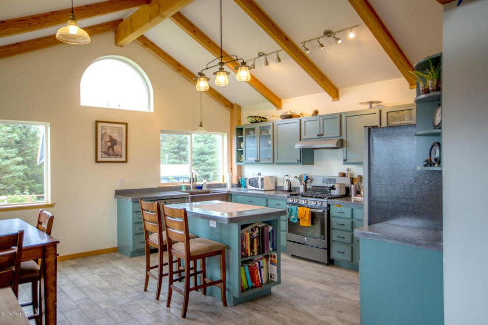This is an example of a large country u-shaped eat-in kitchen in Other with a farmhouse sink, recessed-panel cabinets, turquoise cabinets, concrete benchtops, grey splashback, stone tile splashback, stainless steel appliances, ceramic floors, with island, grey floor, grey benchtop and wood.