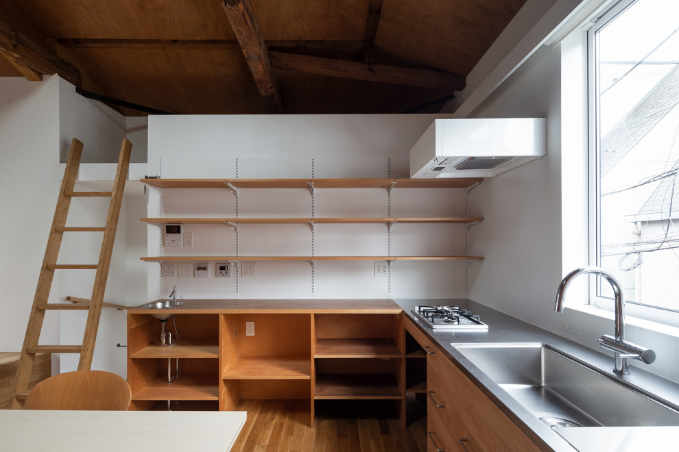 Foto på ett litet brun kök, med en integrerad diskho, luckor med profilerade fronter, skåp i mellenmörkt trä, bänkskiva i rostfritt stål, vitt stänkskydd, rostfria vitvaror, mellanmörkt trägolv och brunt golv