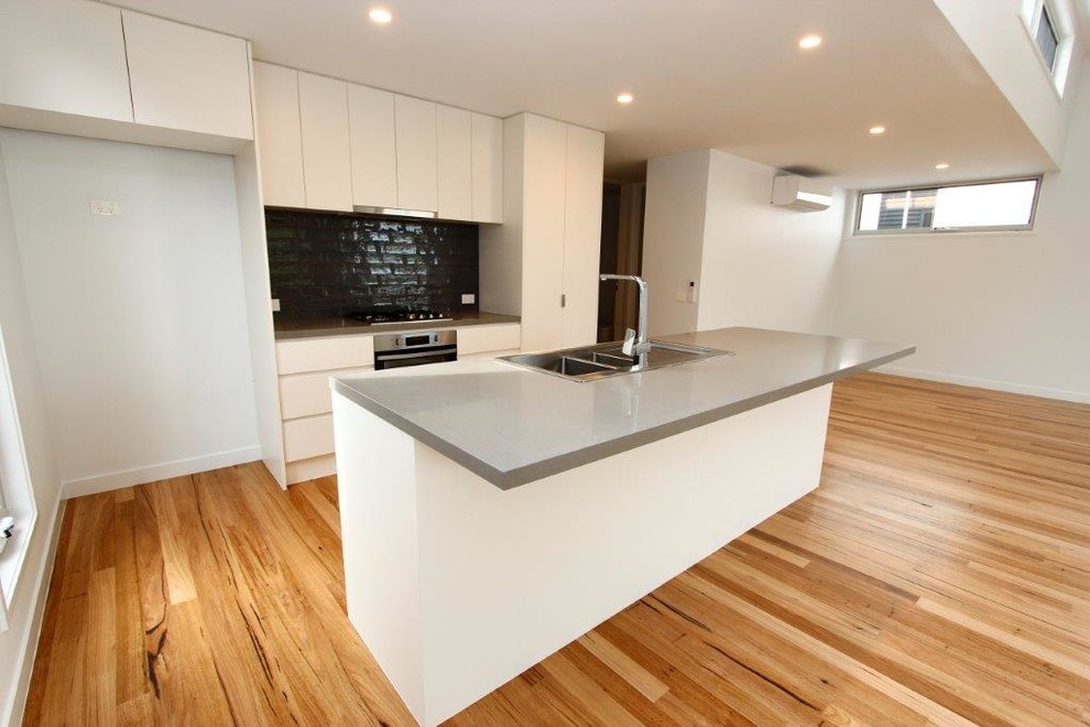 Mid-sized modern galley eat-in kitchen in Melbourne with a double-bowl sink, open cabinets, white cabinets, quartz benchtops, grey splashback, ceramic splashback, stainless steel appliances, light hardwood floors and with island.