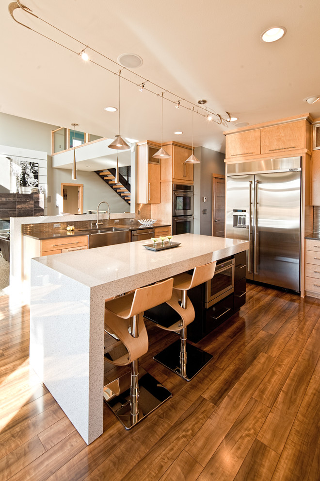 Open concept kitchen - mid-sized contemporary u-shaped dark wood floor open concept kitchen idea in Other with a farmhouse sink, flat-panel cabinets, light wood cabinets, solid surface countertops, metallic backsplash, metal backsplash, stainless steel appliances and an island