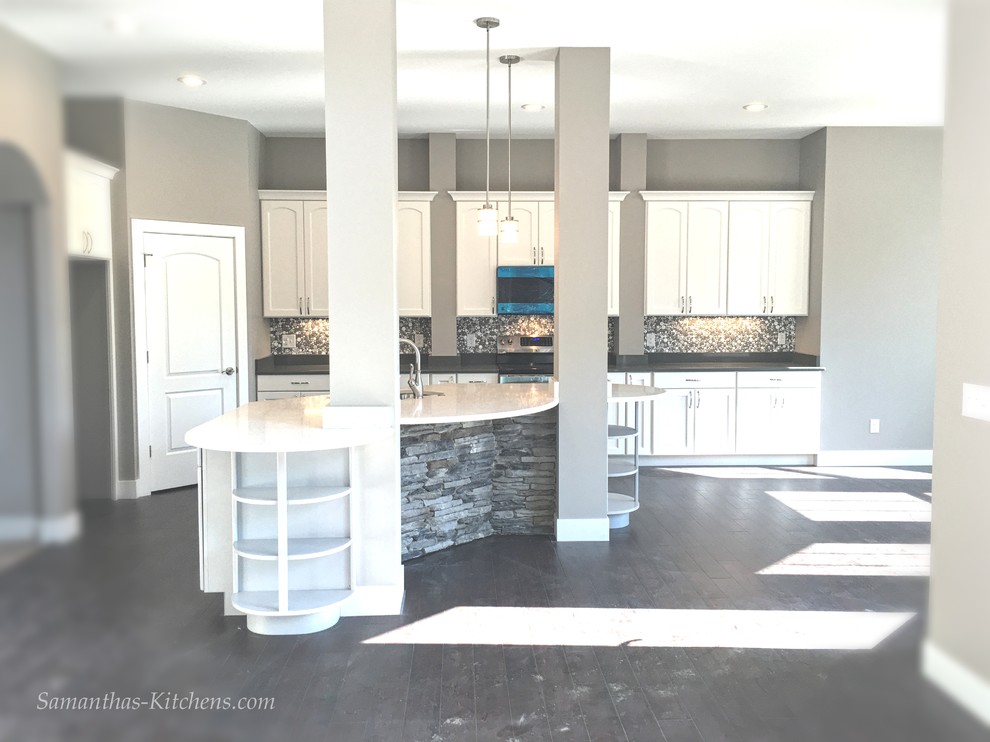 Mid-sized transitional l-shaped dark wood floor home design photo with an undermount sink, recessed-panel cabinets, white cabinets, quartz countertops, gray backsplash, ceramic backsplash, stainless steel appliances and an island