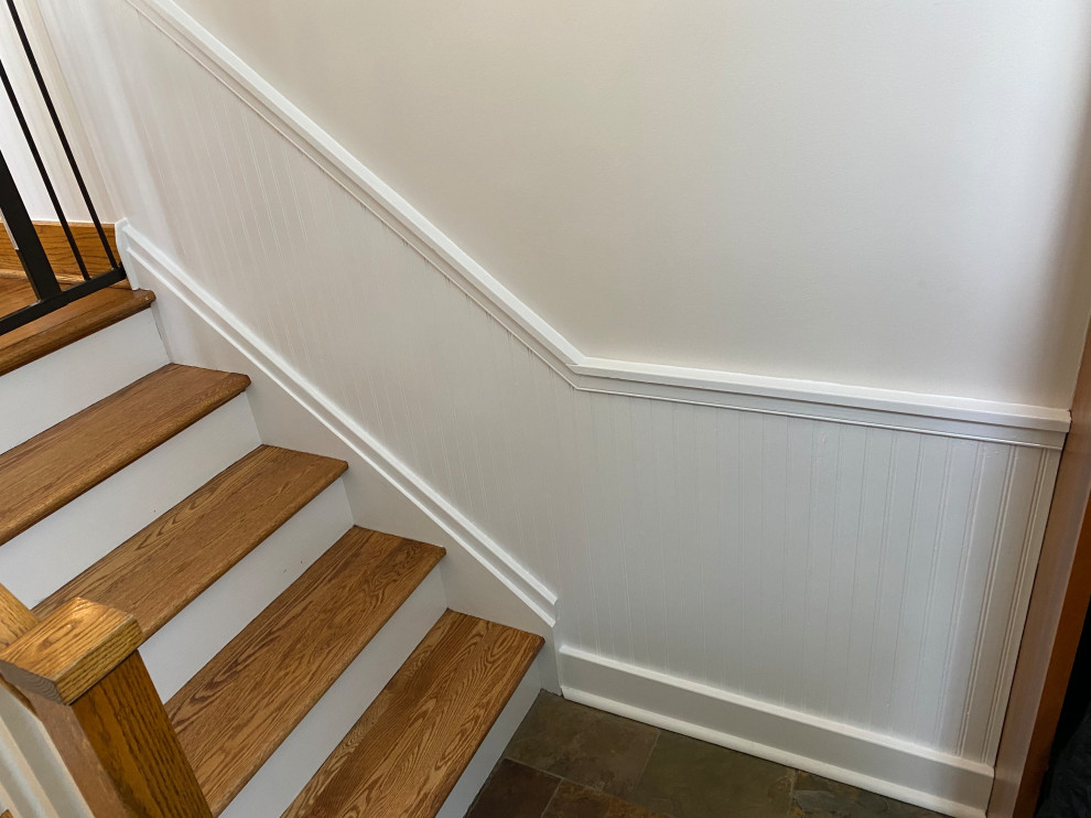 Diseño de escalera curva clásica pequeña con escalones de madera, contrahuellas de madera, barandilla de madera y boiserie
