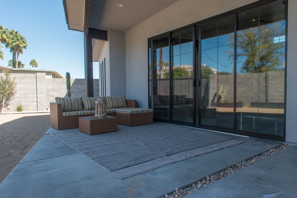 This is an example of a small industrial backyard patio in Phoenix with concrete slab and a roof extension.