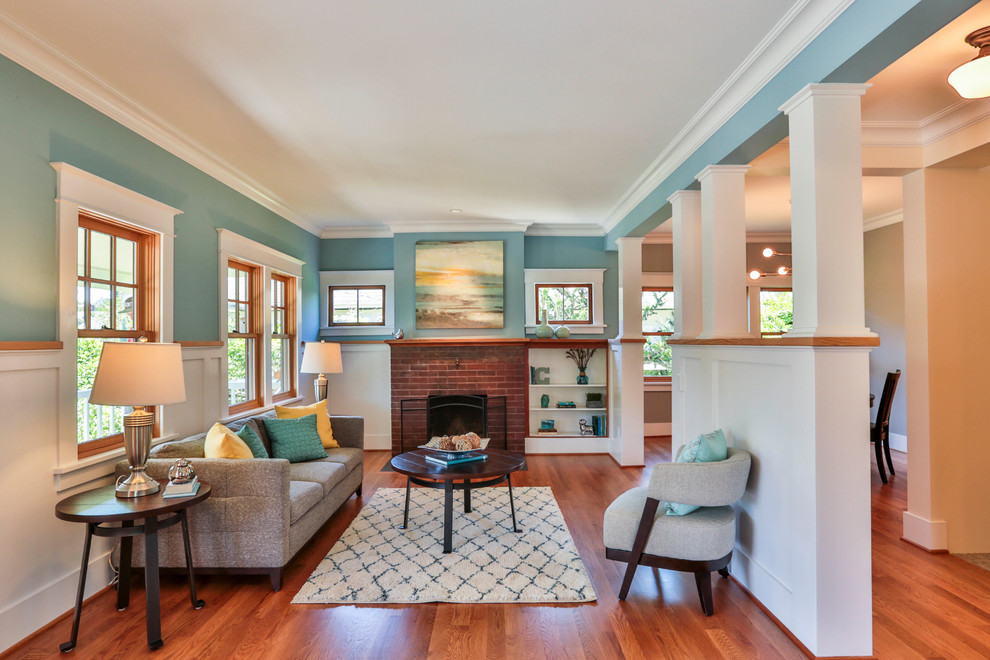 Photo of a mid-sized arts and crafts formal open concept living room in Seattle with blue walls, medium hardwood floors, a standard fireplace, a brick fireplace surround, no tv and brown floor.