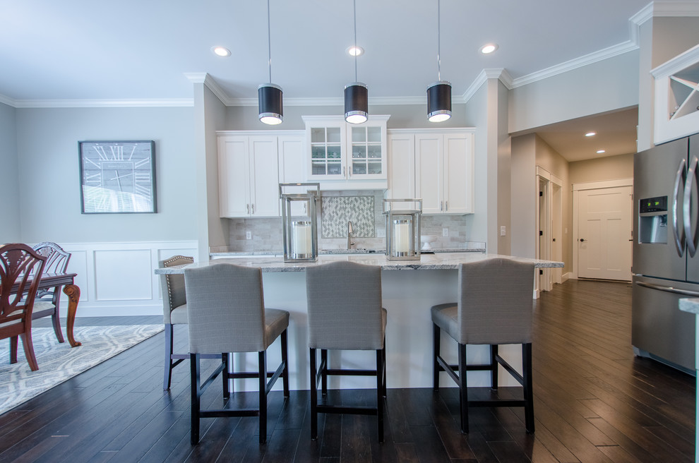 Example of a mid-sized transitional single-wall dark wood floor eat-in kitchen design with recessed-panel cabinets, white cabinets, granite countertops, stone tile backsplash, stainless steel appliances and an island
