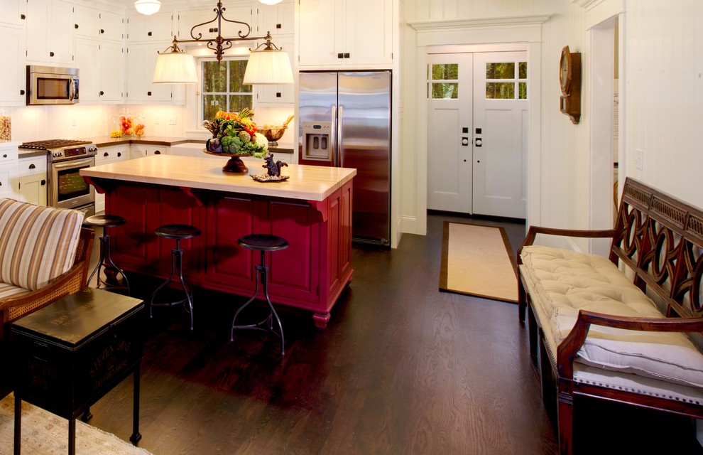 Example of a mid-sized eclectic dark wood floor eat-in kitchen design in Milwaukee with a farmhouse sink, recessed-panel cabinets, white cabinets, white backsplash, stainless steel appliances and an island