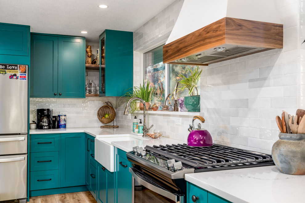 This is an example of a mid-sized eclectic eat-in kitchen in Other with an integrated sink, shaker cabinets, blue cabinets, quartz benchtops, white splashback, ceramic splashback, stainless steel appliances, vinyl floors, with island, beige floor and white benchtop.