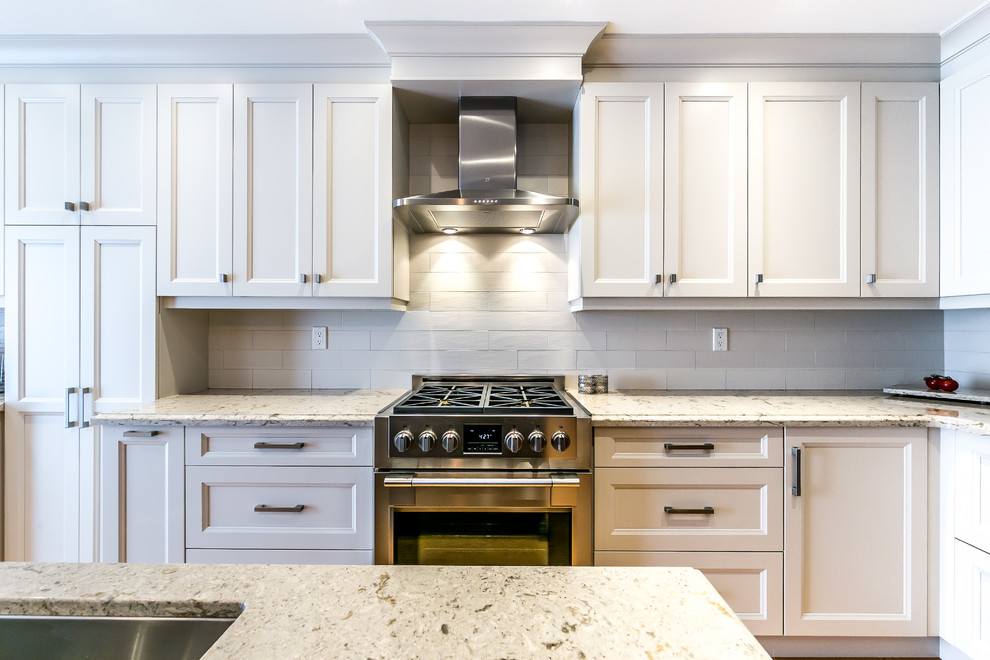 Mid-sized transitional l-shaped brown floor kitchen photo in Toronto with a double-bowl sink, white cabinets, white backsplash, stainless steel appliances and an island