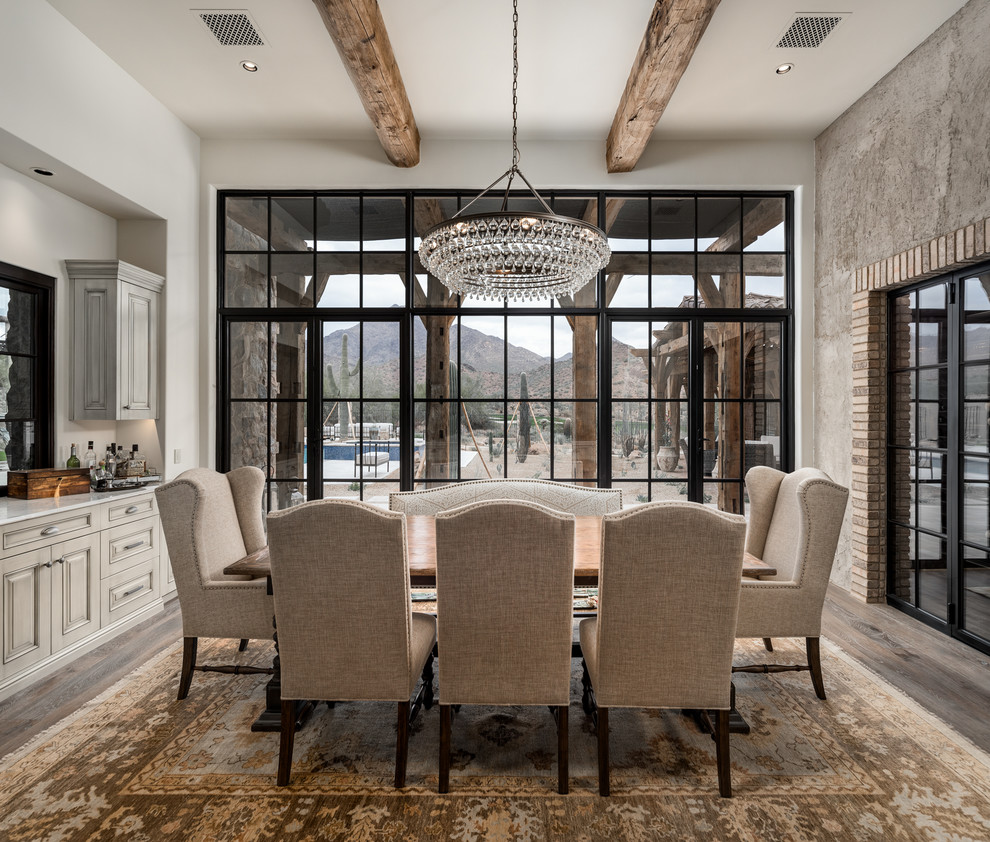 Design ideas for an expansive country separate dining room in Phoenix with multi-coloured walls, dark hardwood floors, a standard fireplace, a stone fireplace surround, brown floor, exposed beam and brick walls.