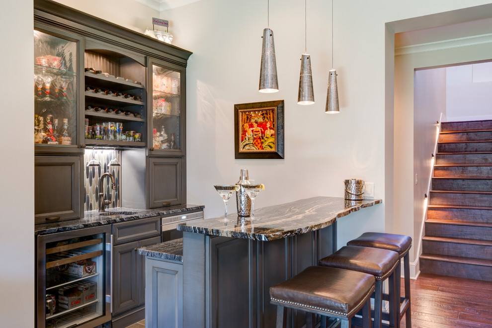 Inspiration for a mid-sized transitional seated home bar in Other with recessed-panel cabinets, grey cabinets, grey splashback, an undermount sink, mosaic tile splashback and medium hardwood floors.