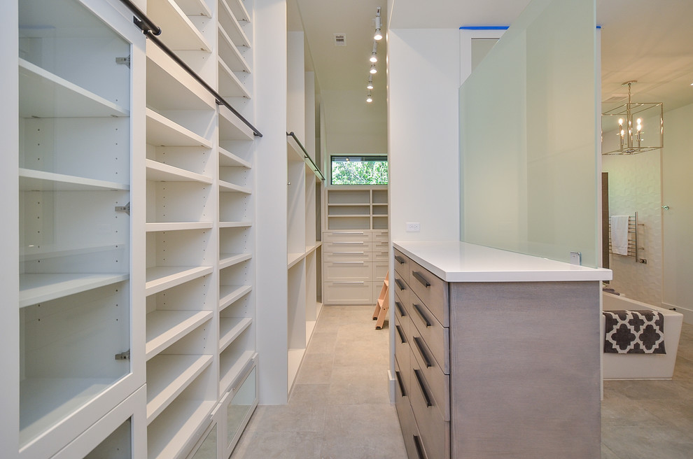 Photo of a mid-sized transitional gender-neutral walk-in wardrobe in Houston with flat-panel cabinets, grey cabinets, porcelain floors and grey floor.