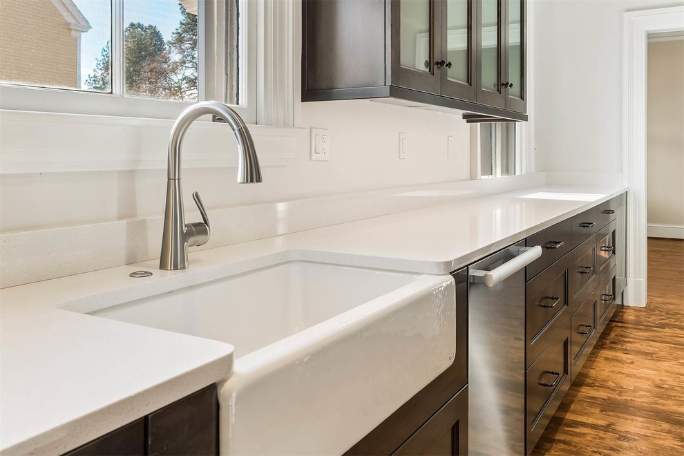 Inspiration for a mid-sized transitional u-shaped medium tone wood floor enclosed kitchen remodel in Seattle with a farmhouse sink, recessed-panel cabinets, gray cabinets, quartz countertops, white backsplash, ceramic backsplash, stainless steel appliances and an island