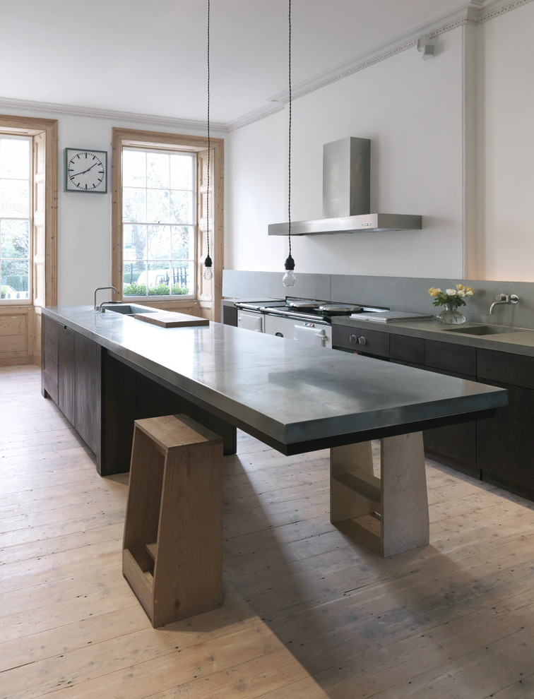 Inspiration for a contemporary kitchen in London with concrete benchtops, an integrated sink, flat-panel cabinets, black cabinets, light hardwood floors, with island and beige floor.