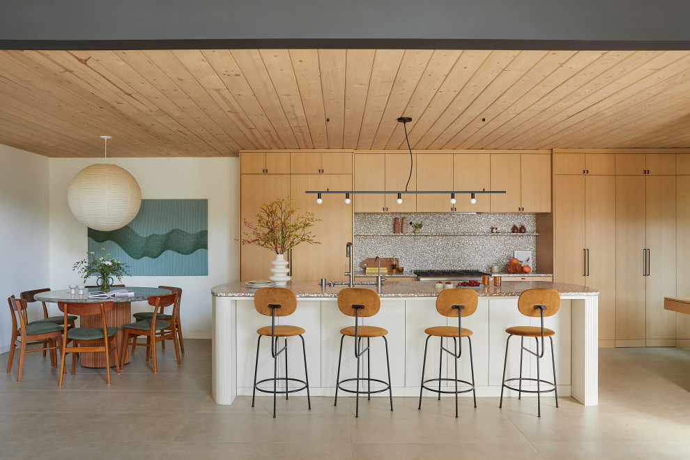 Design ideas for a mid-sized midcentury single-wall open plan kitchen in San Francisco with an undermount sink, flat-panel cabinets, light wood cabinets, terrazzo benchtops, grey splashback, cement tile splashback, panelled appliances, porcelain floors, with island, beige floor, grey benchtop and wood.