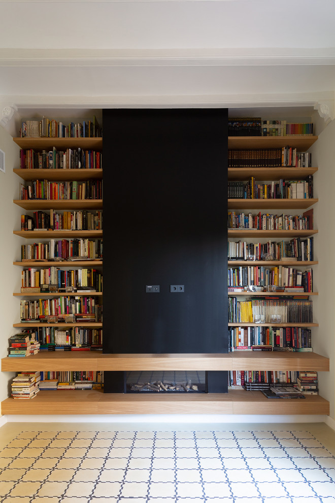 Modelo de biblioteca en casa clásica renovada de tamaño medio con suelo de cemento, suelo beige y vigas vistas