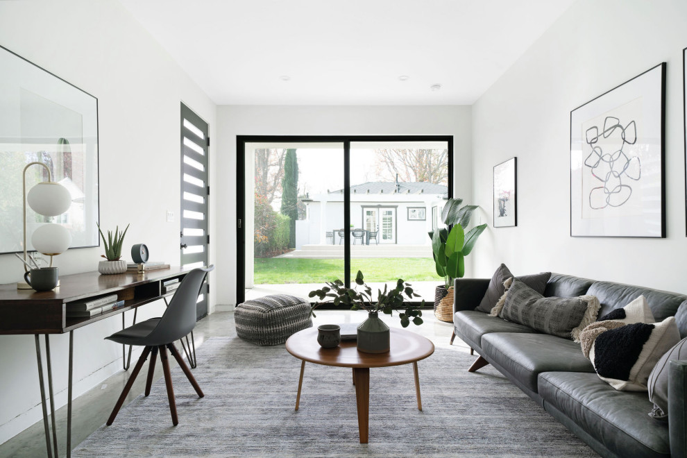 Contemporary living room in Los Angeles with white walls, concrete flooring and grey floors.