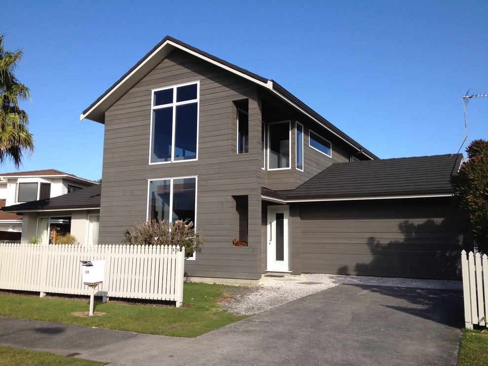 Mid-sized industrial two-storey grey house exterior in Auckland with wood siding, a gable roof and a metal roof.