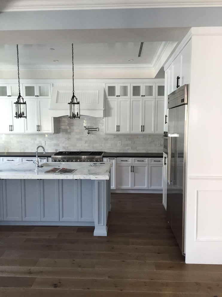 This is an example of a large traditional l-shaped eat-in kitchen in Los Angeles with a single-bowl sink, shaker cabinets, white cabinets, marble benchtops, white splashback, stone tile splashback, stainless steel appliances, light hardwood floors and with island.