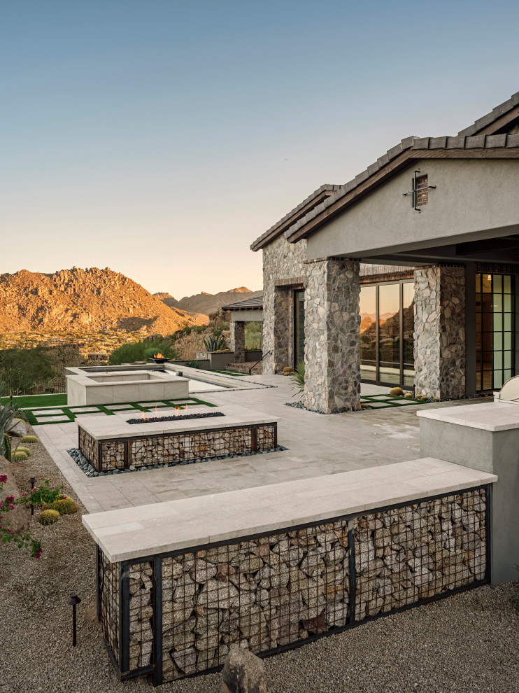 Inspiration for a large southwestern gray two-story stone house exterior remodel in Phoenix with a hip roof, a tile roof and a black roof
