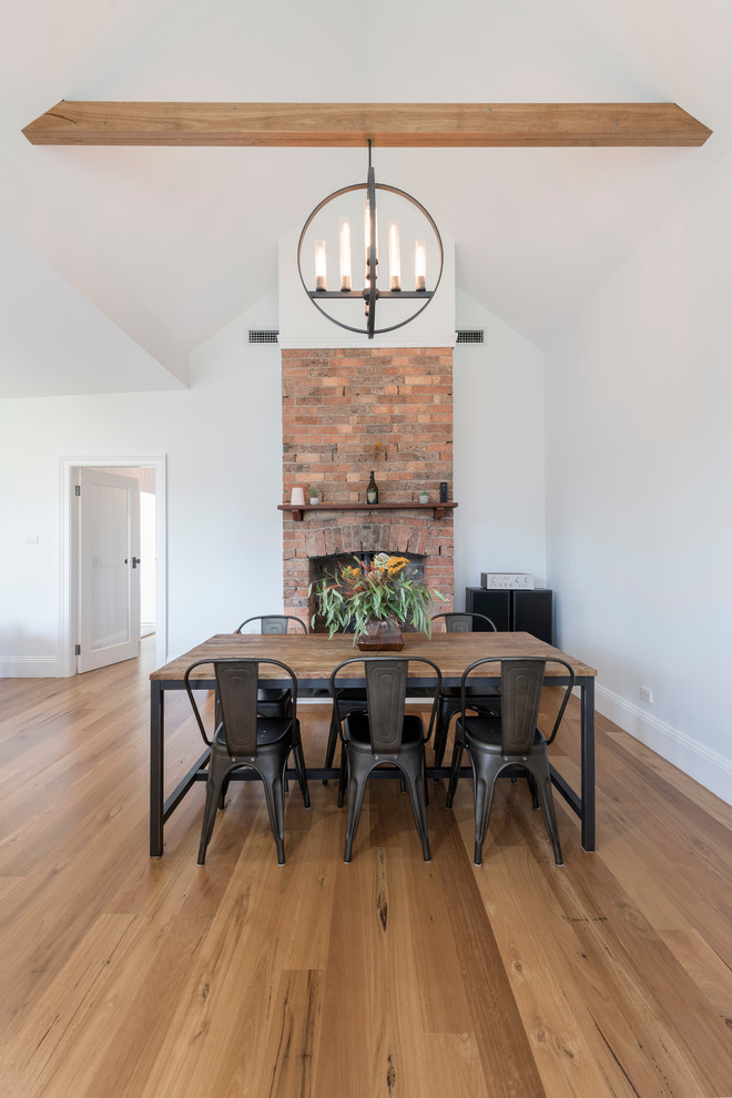 This is an example of a transitional dining room in Newcastle - Maitland with white walls, medium hardwood floors, a standard fireplace, a brick fireplace surround and brown floor.