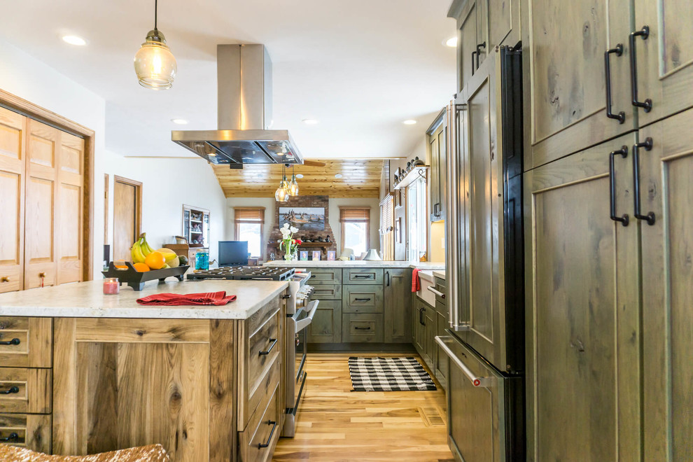 Example of a large mountain style light wood floor and brown floor open concept kitchen design with beaded inset cabinets, distressed cabinets, granite countertops, an island and white countertops