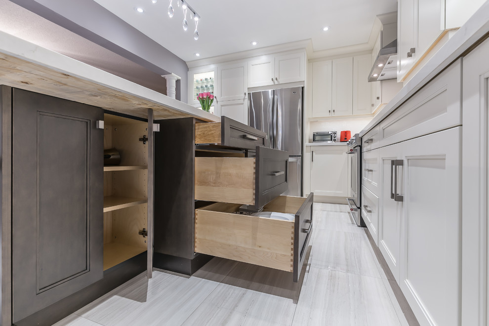 Example of a mid-sized transitional l-shaped porcelain tile eat-in kitchen design in Toronto with a drop-in sink, recessed-panel cabinets, white cabinets, quartz countertops, stainless steel appliances and an island