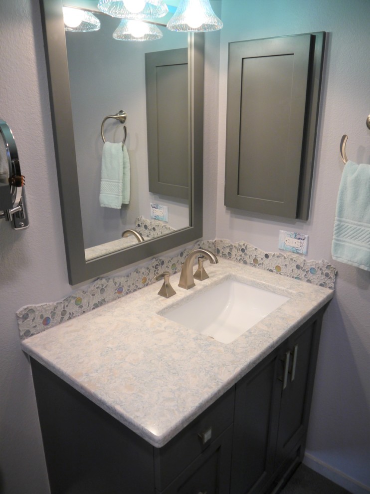 Inspiration for a mid-sized transitional master bathroom in Seattle with shaker cabinets, grey cabinets, a two-piece toilet, gray tile, porcelain tile, white walls, porcelain floors, an undermount sink, solid surface benchtops, grey floor, a hinged shower door and multi-coloured benchtops.
