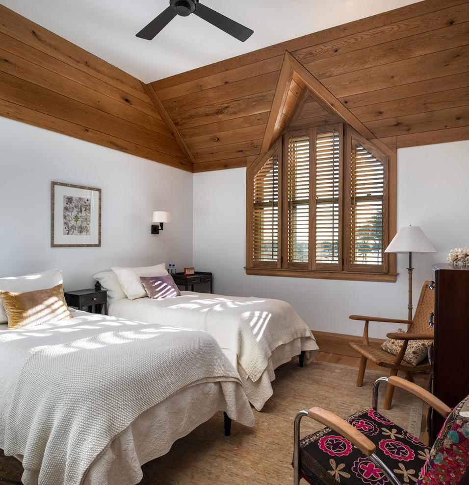 Photo of a beach style bedroom in New York with white walls and medium hardwood floors.