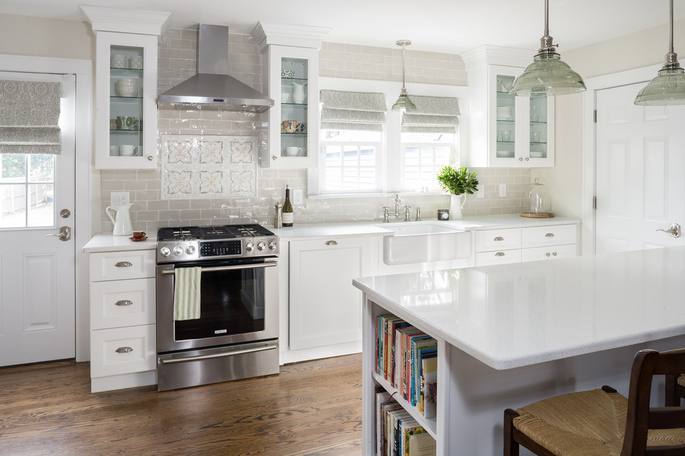 Mid-sized country eat-in kitchen in New York with a farmhouse sink, recessed-panel cabinets, white cabinets, quartz benchtops, grey splashback, ceramic splashback, stainless steel appliances, medium hardwood floors and a peninsula.