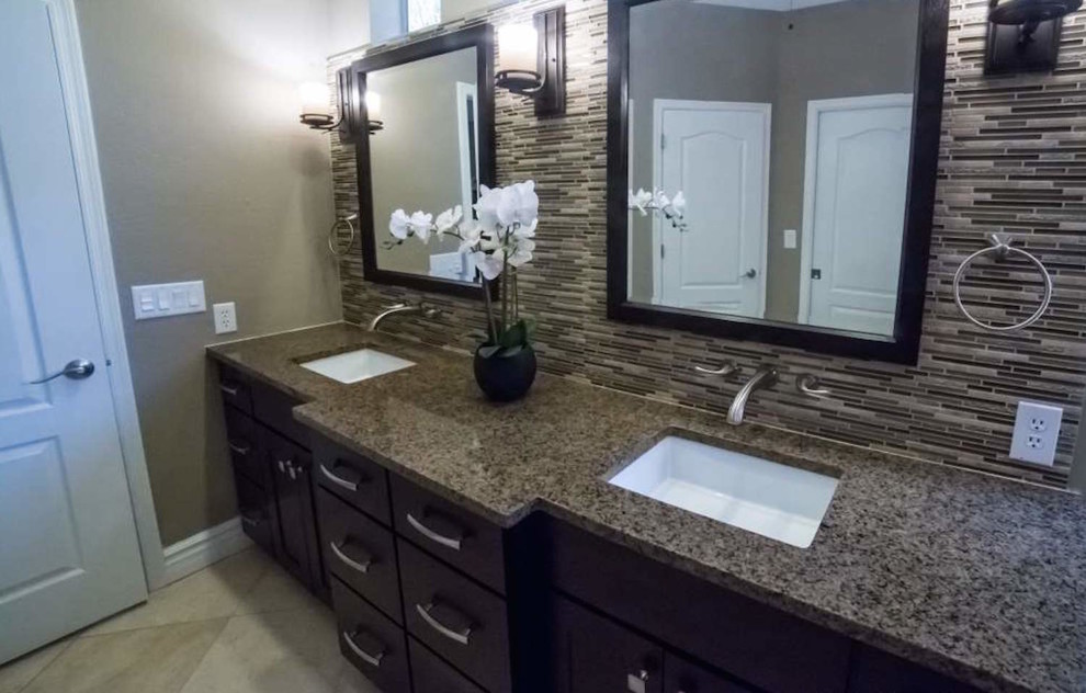 Mid-sized transitional master bathroom in Phoenix with shaker cabinets, dark wood cabinets, a drop-in tub, a corner shower, a two-piece toilet, brown tile, porcelain tile, beige walls, pebble tile floors and granite benchtops.