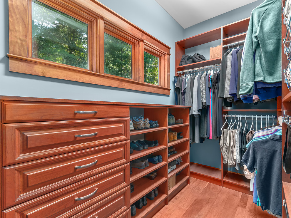 Example of a mid-sized arts and crafts men's medium tone wood floor and brown floor walk-in closet design with raised-panel cabinets and medium tone wood cabinets