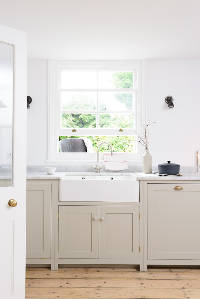 Mid-sized country open plan kitchen in Sussex with a farmhouse sink, shaker cabinets, grey cabinets, marble benchtops, white splashback, subway tile splashback, light hardwood floors and with island.