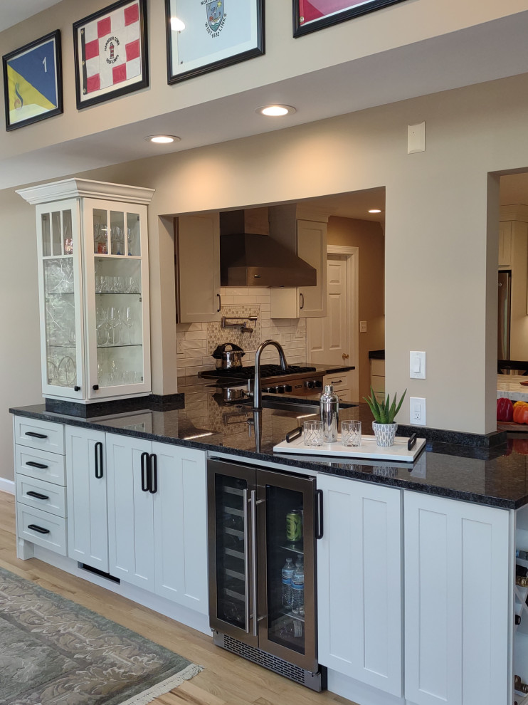 Design ideas for a large transitional u-shaped open plan kitchen in Baltimore with a single-bowl sink, shaker cabinets, white cabinets, marble benchtops, white splashback, porcelain splashback, stainless steel appliances, medium hardwood floors, with island and white benchtop.