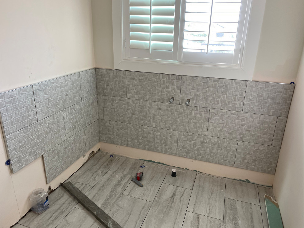 Design ideas for a mid-sized modern master bathroom in Orange County with a freestanding tub, a corner shower, gray tile, ceramic tile, white walls, ceramic floors, blue floor, a hinged shower door and a niche.