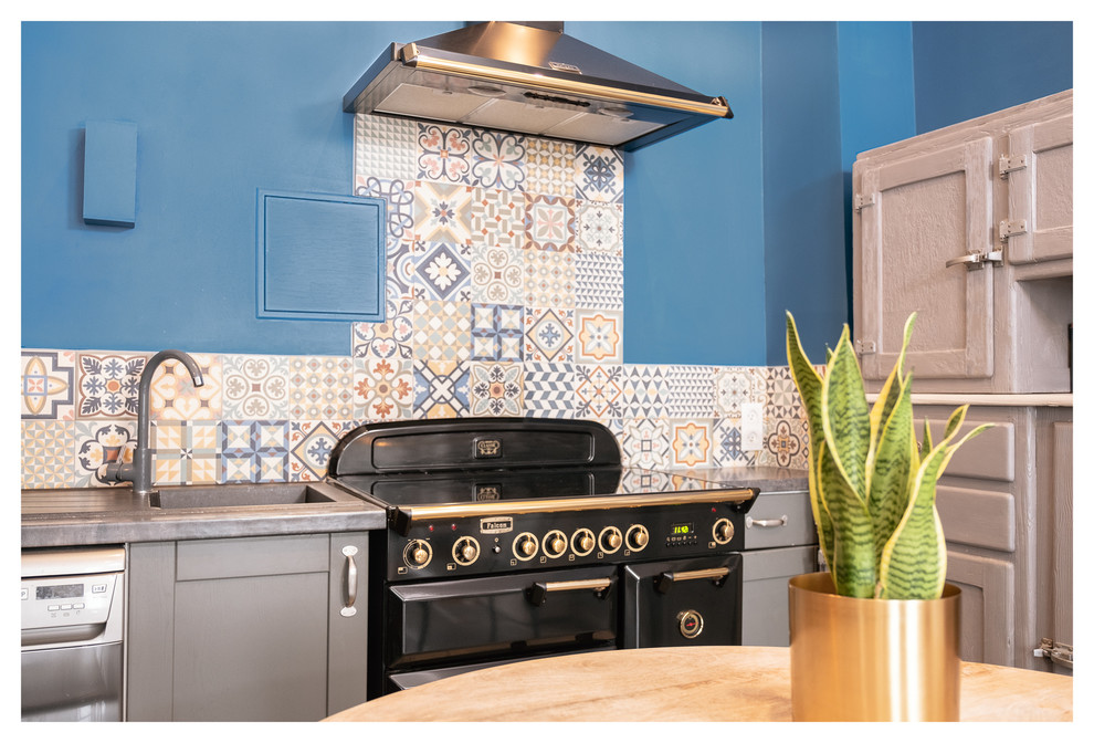 This is an example of a small midcentury l-shaped open plan kitchen in Toulouse with multi-coloured splashback, cement tile splashback, black appliances, no island, grey floor and grey benchtop.